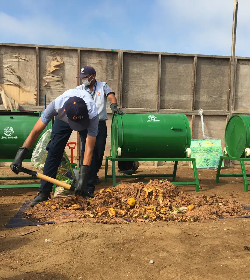 Operario de Lima Compost cargando residuos orgánicos junto a las composteras de cilindro en la planta