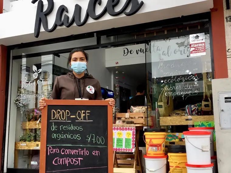 Supervisora de Lima Compost atendiendo un punto de acopio, con el cartel que indica dónde dejar los residuos