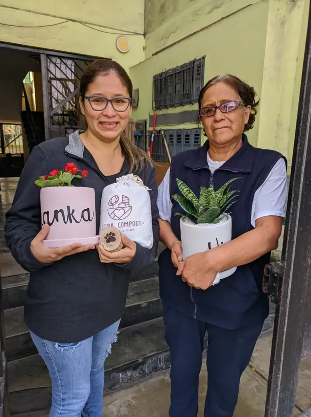 Dos mujeres recibiendo la maceta de Vianka y una planta