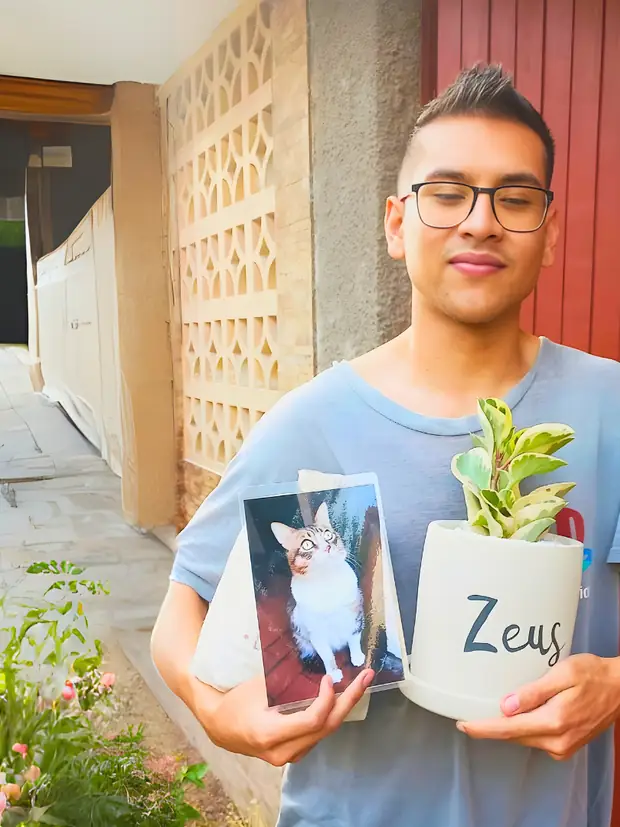 Joven sosteniendo la maceta de Zeus junto a la foto de su perro