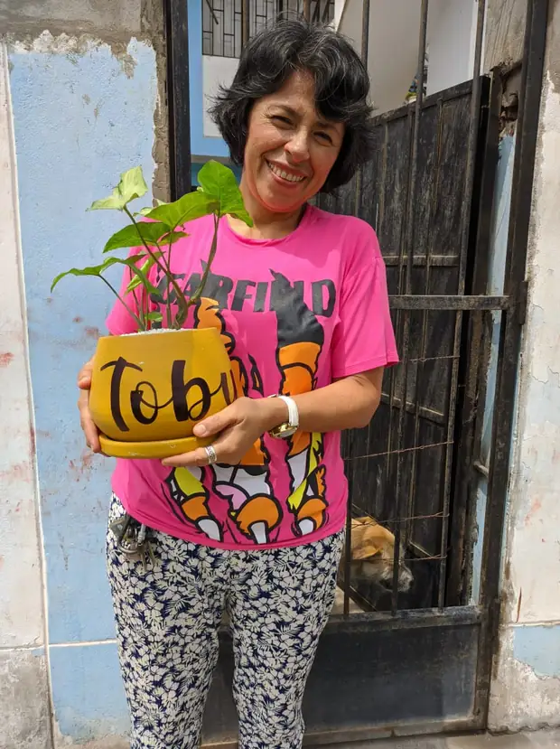 Mujer sonriendo con la maceta amarilla de Toby en las manos