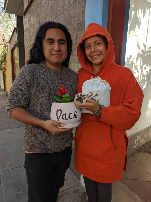 Pareja sosteniendo la maceta de Paco y el token con su huella